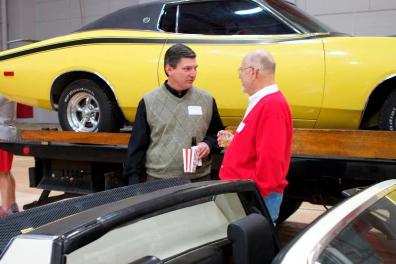 a man talking to another man in a car showroom