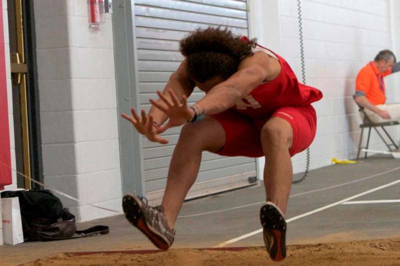a person in a red uniform jumping over sand