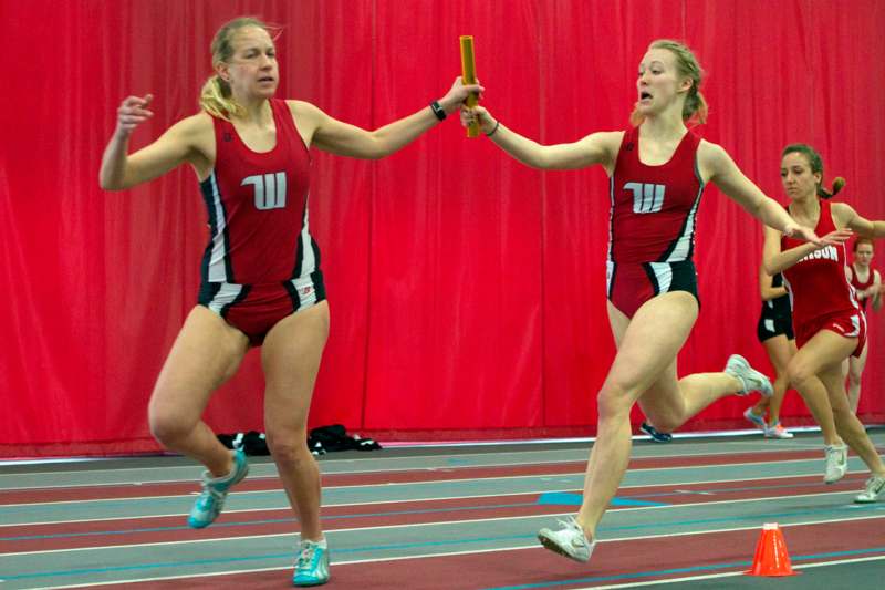 two women in athletic uniforms holding batons