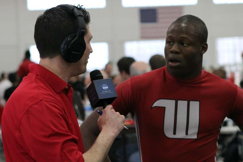 a man in red shirt talking to another man in headphones