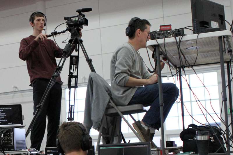 a man sitting in a chair with a man on a tripod