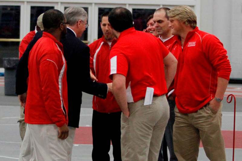 a group of men in red shirts shaking hands