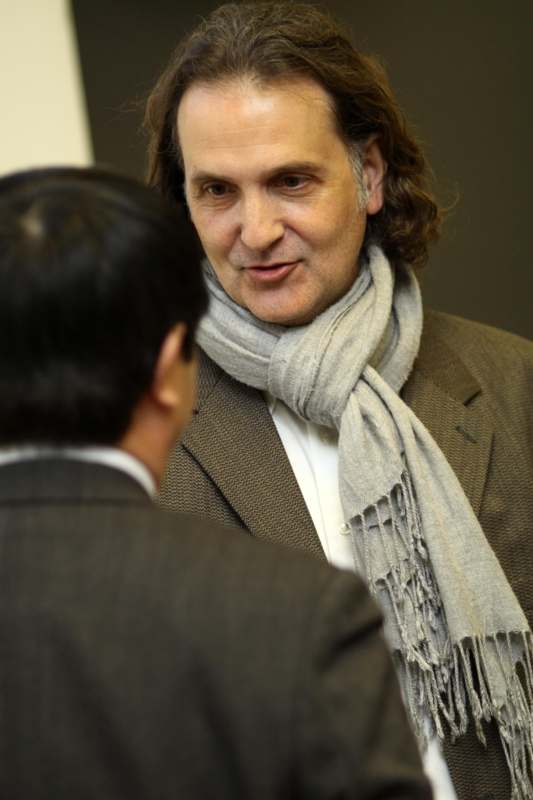 a man wearing a scarf and a jacket talking to another man