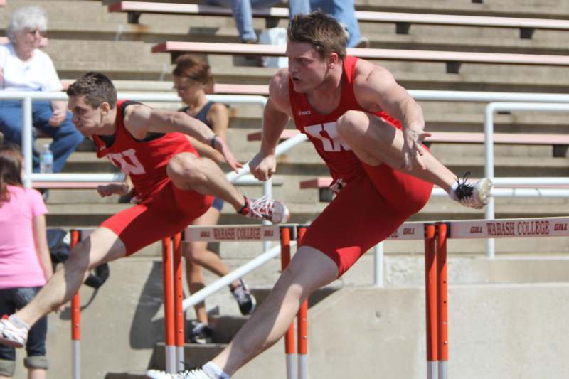 a group of men in red uniforms jumping over hurdles