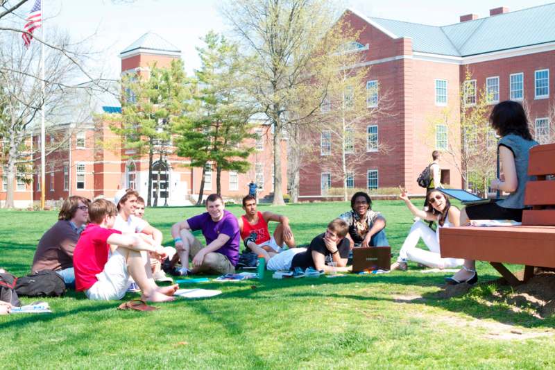 a group of people sitting on grass in front of a building