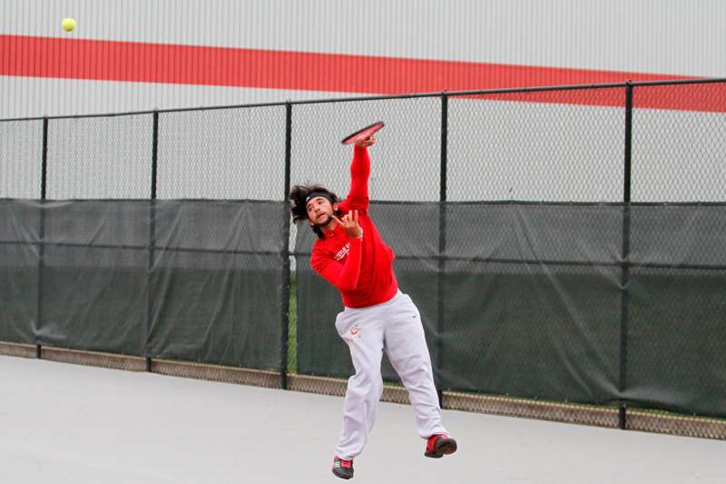 a man in red shirt and white pants playing tennis