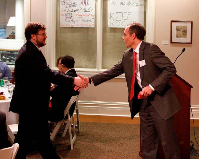 a man in a suit shaking hands with another man