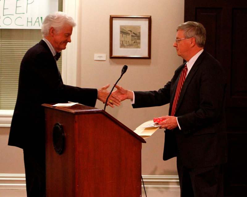 a man shaking hands with another man at a podium
