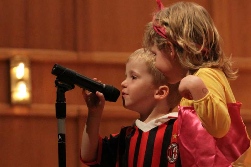 a boy and girl singing into a microphone