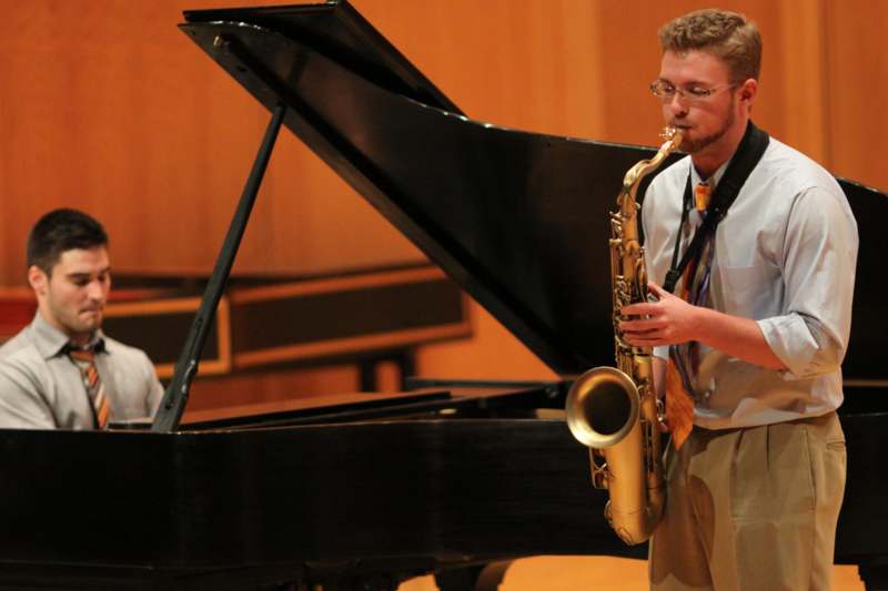 a man playing a saxophone next to a piano
