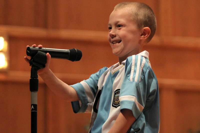 a boy smiling at a microphone