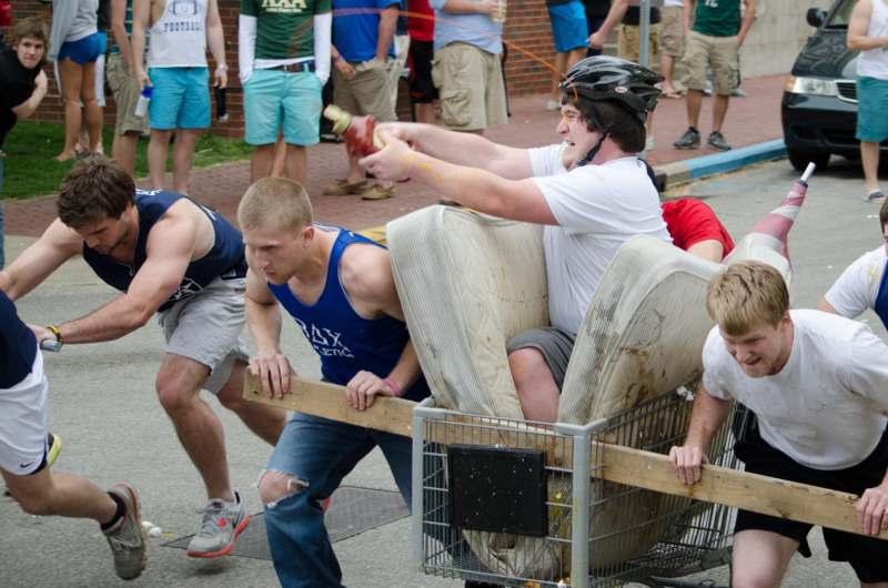 a group of men pushing a cart with a man in a chair
