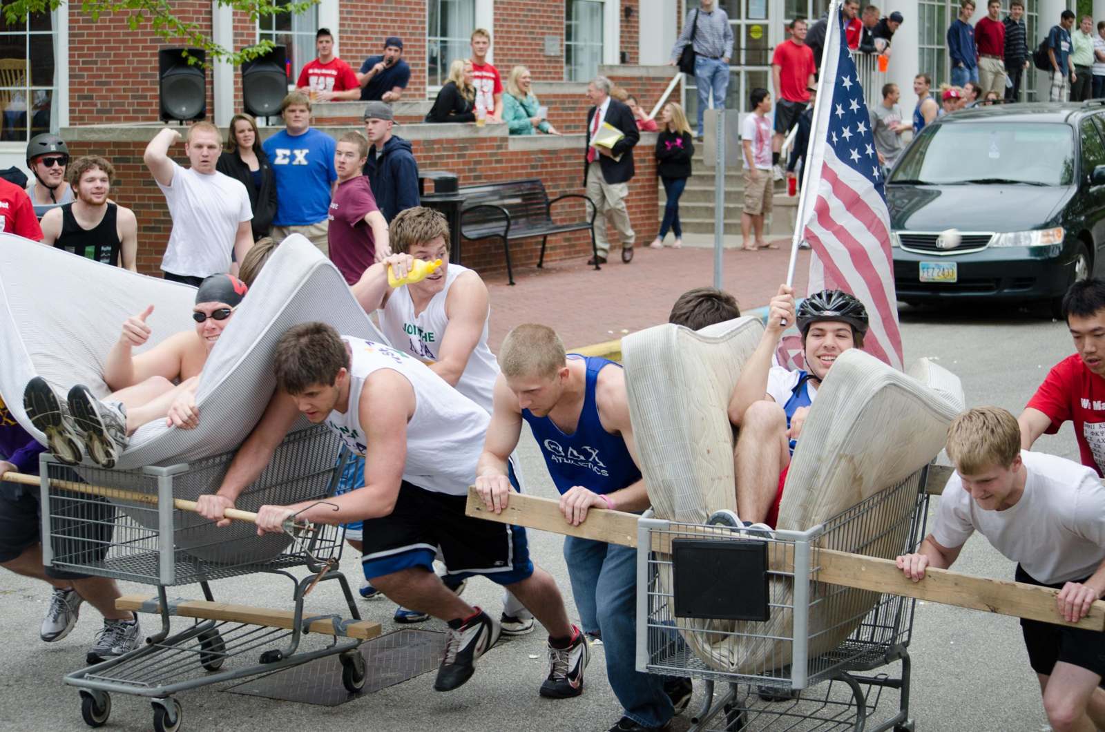 a group of people pushing a cart with mattresses