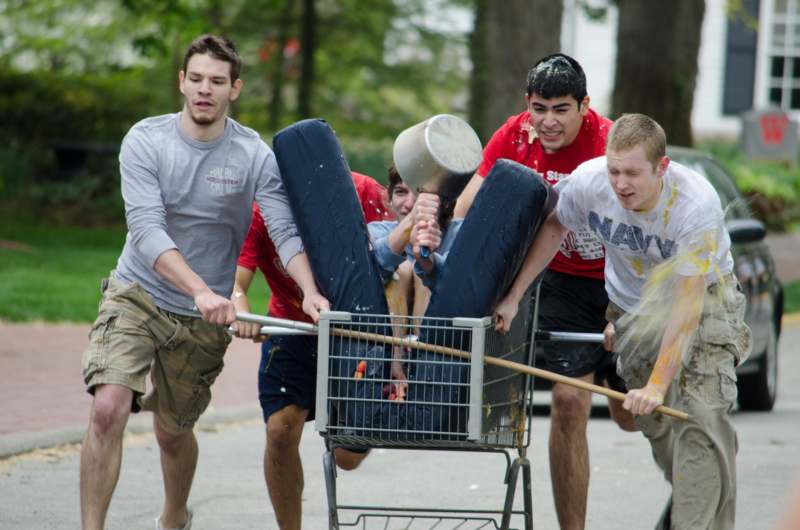 a group of men pushing a shopping cart with a bucket of water on it