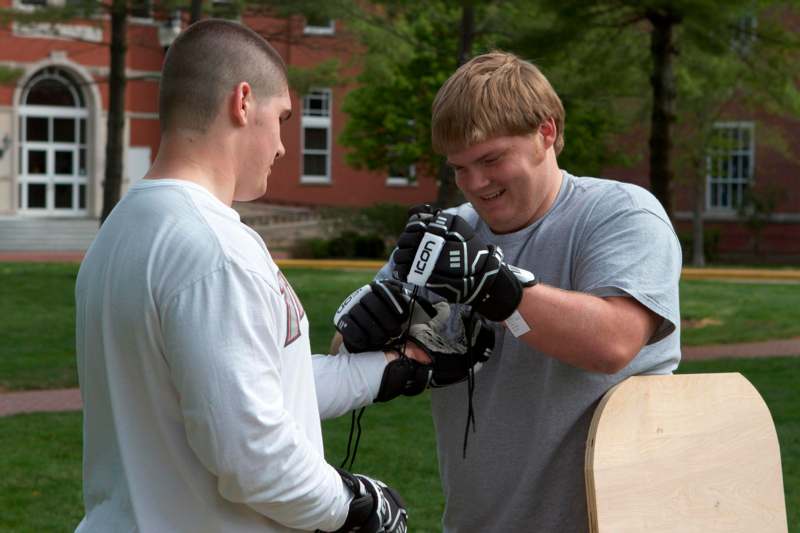 a man wearing gloves and smiling while another man is wearing gloves