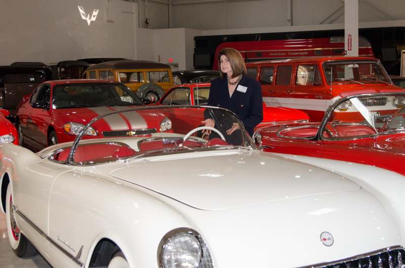 a woman standing in front of a white and red car