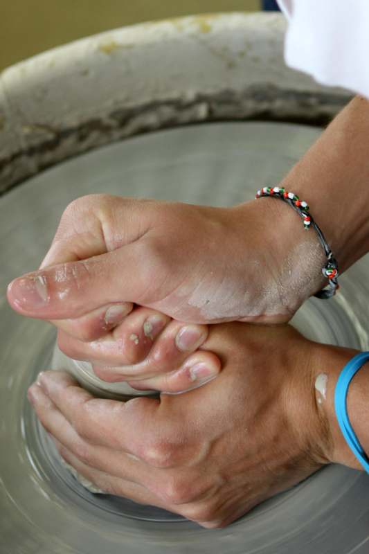 a person's hands holding a clay pot