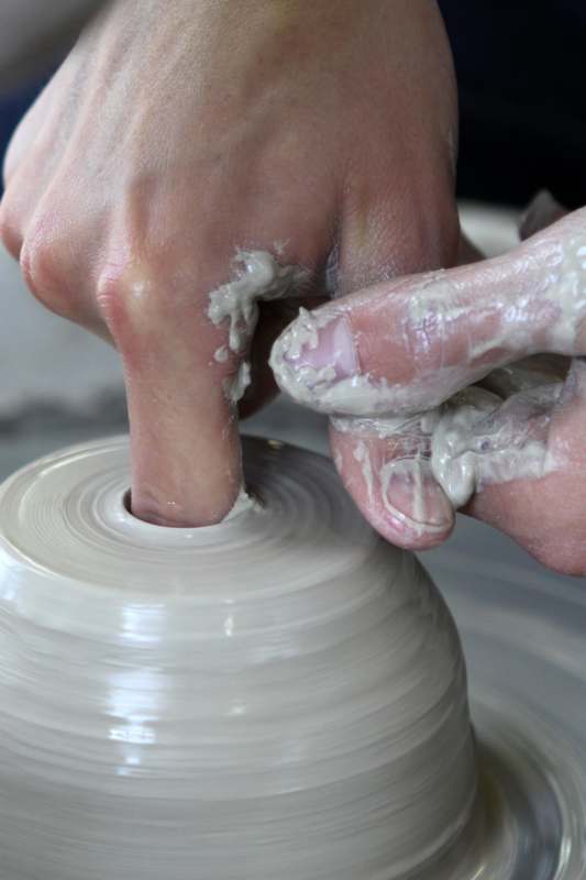 a person's hands making a clay pot
