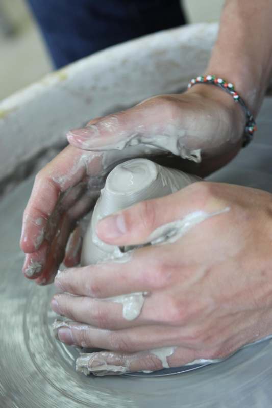 a person's hands making a clay object