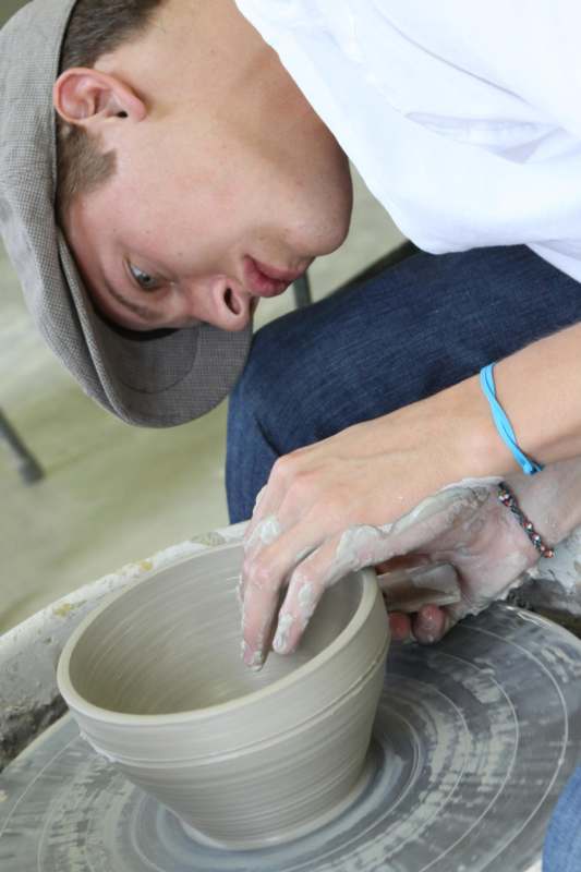 a man in a hat working on a pottery wheel