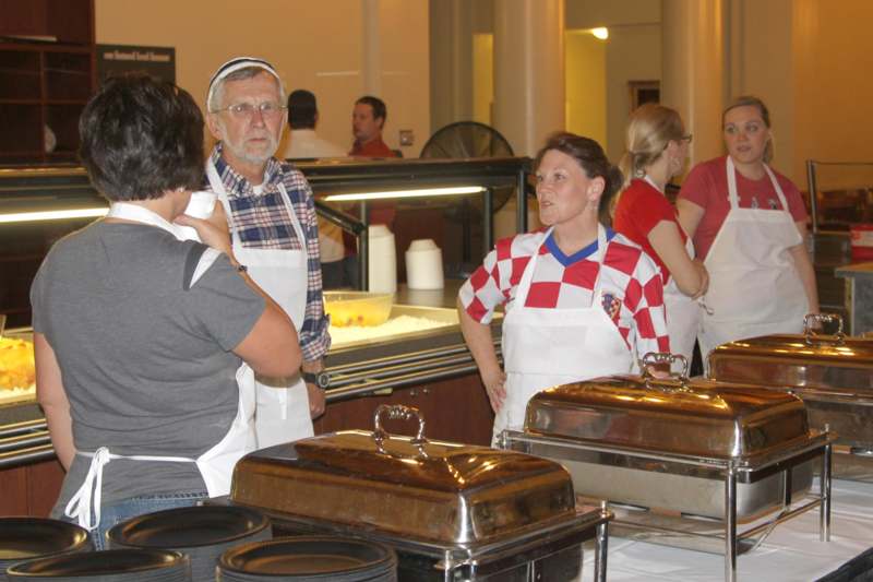 a group of people in aprons standing in front of a buffet