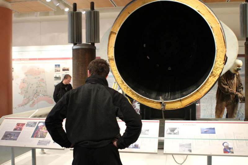a man looking at a large black cylinder
