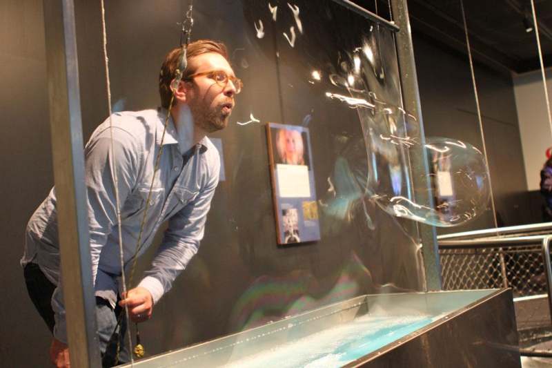 a man blowing bubbles in a glass wall