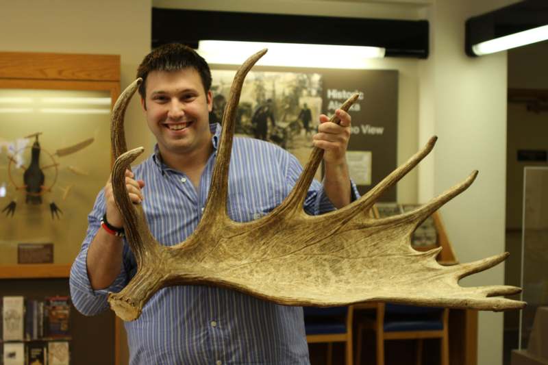 a man holding a large antler