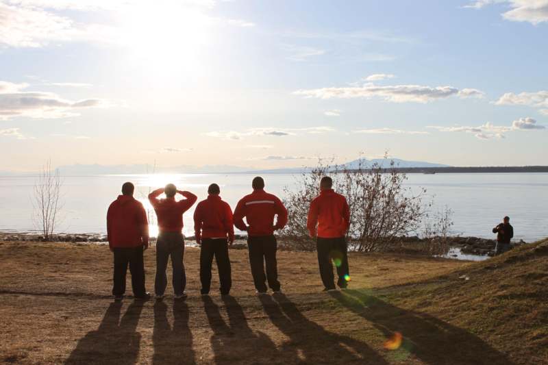 a group of men standing in a line by a body of water