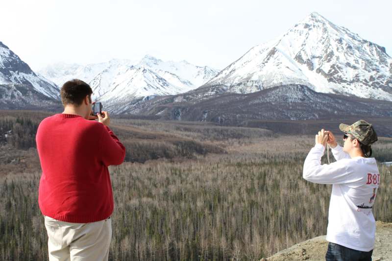 a couple of men taking a picture of a mountain range