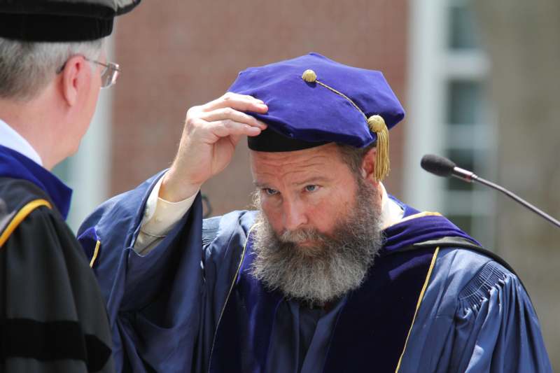 a man wearing a blue graduation cap and gown