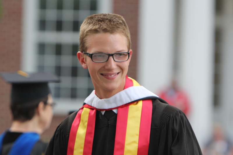 a man wearing a graduation gown and glasses