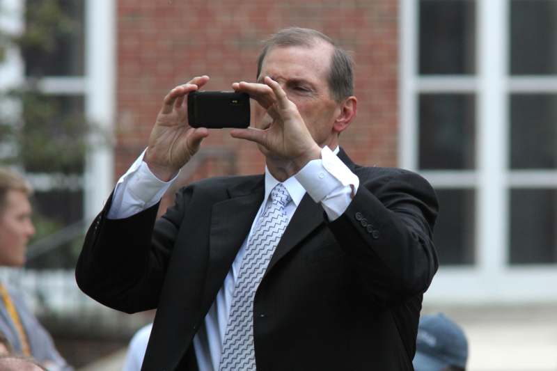 a man in a suit taking a picture with a cell phone