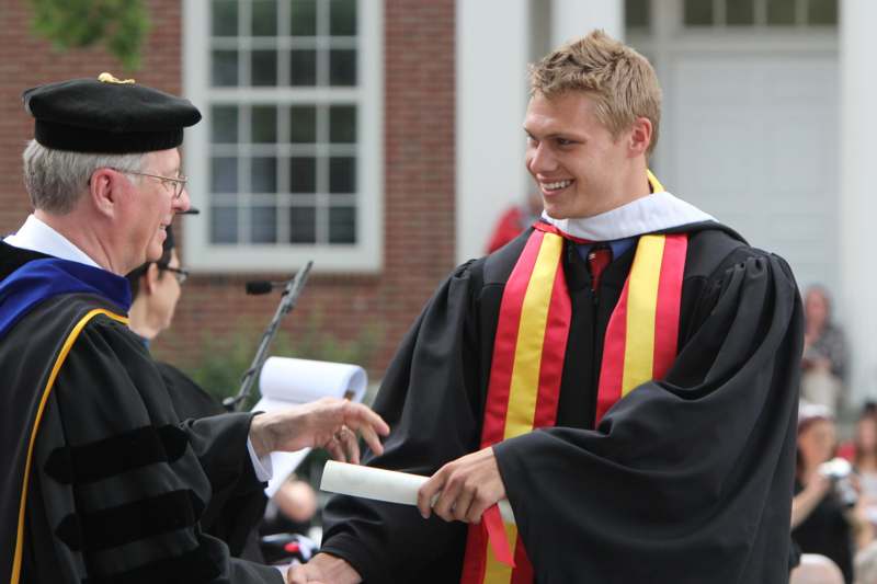 a man in a graduation gown smiling