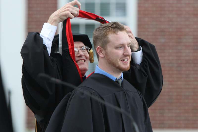 a man in a cap and gown holding a red and black tie