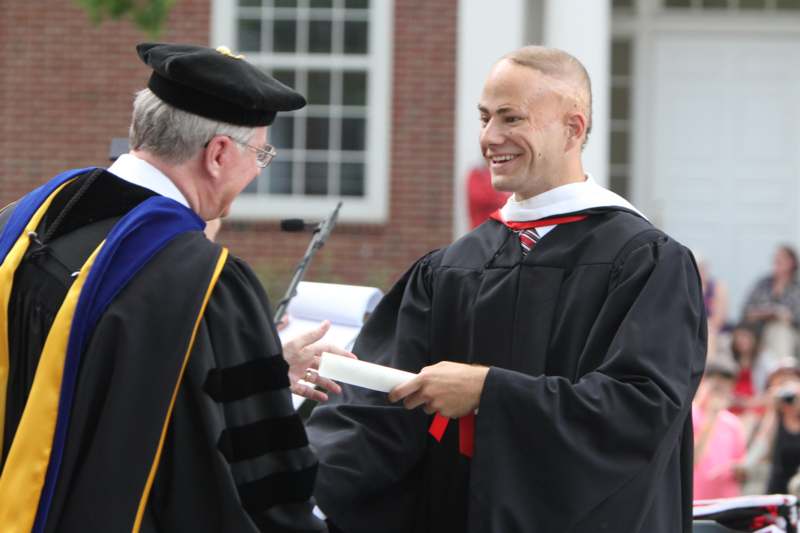 a man in a graduation gown talking to a man in a graduation gown