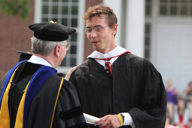 a man in a graduation gown talking to a man