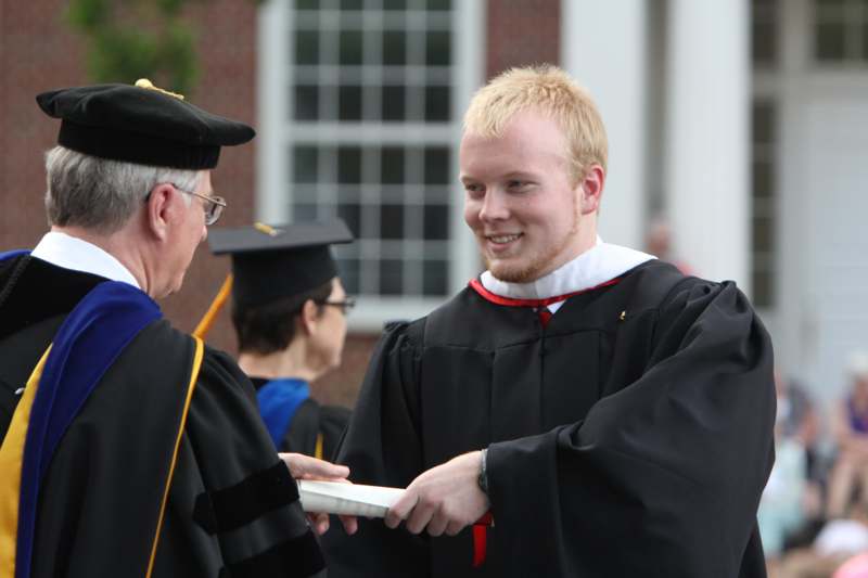 a man in a graduation gown holding a plate