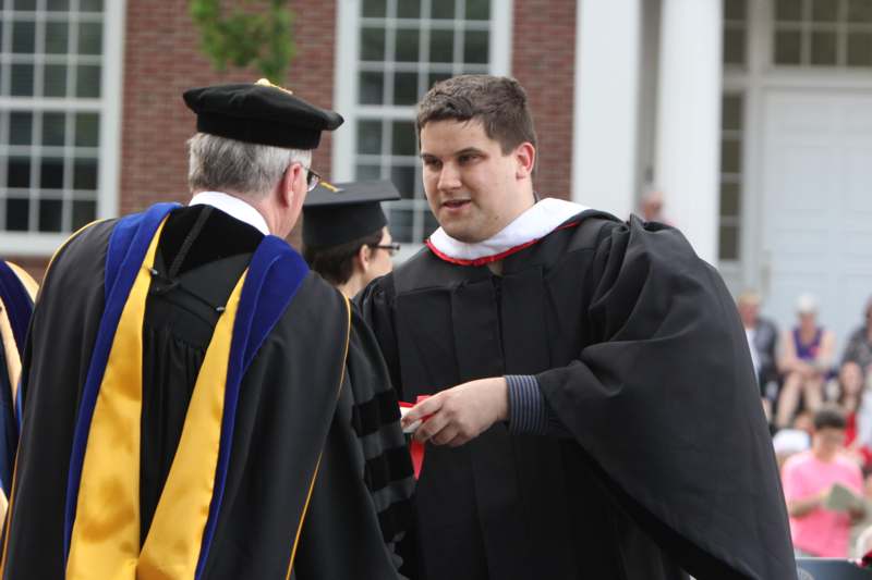 a man in a graduation gown talking to a man in a cap