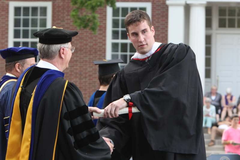 a man in a black robe shaking hands with a man in a black robe