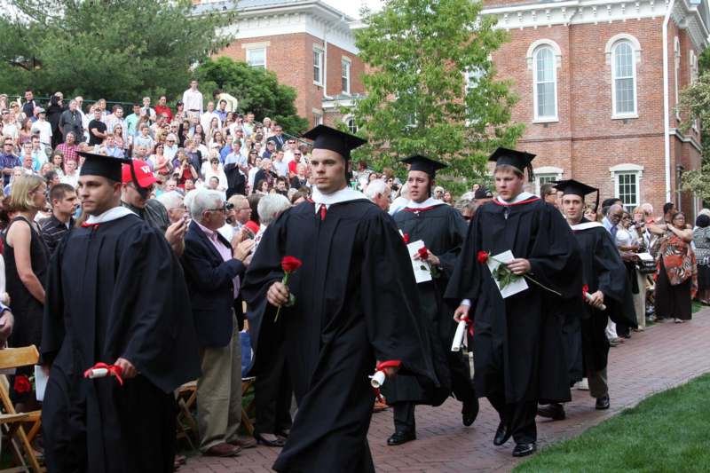 a group of graduates walking down a brick path