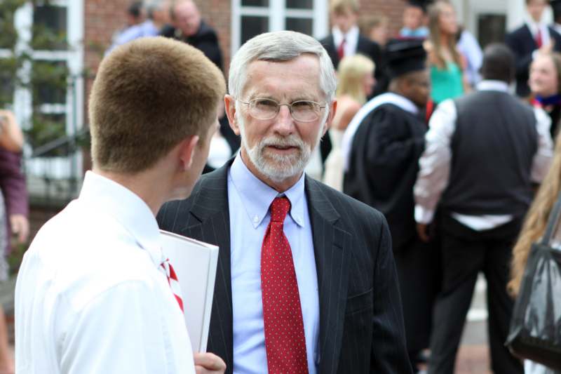 a man in a suit and tie talking to a young man