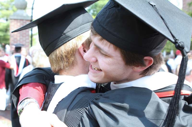 a group of people in graduation gowns and caps hugging