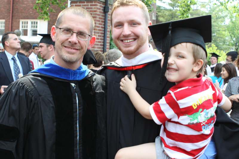 a man holding a child in a graduation gown