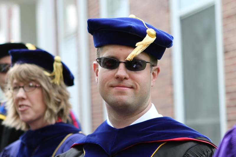 a man wearing a blue graduation cap and sunglasses