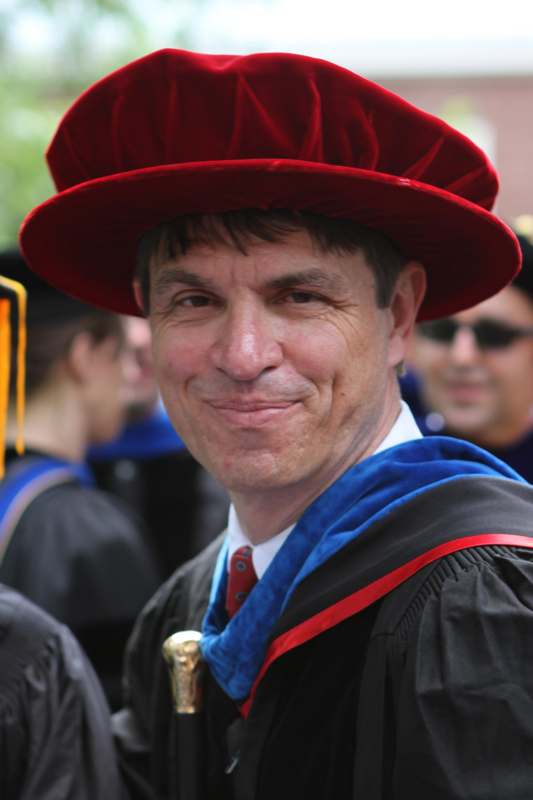 a man wearing a red hat and gown