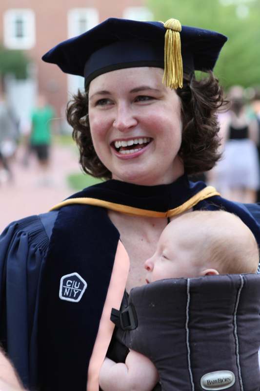 a woman in a graduation gown and cap holding a baby