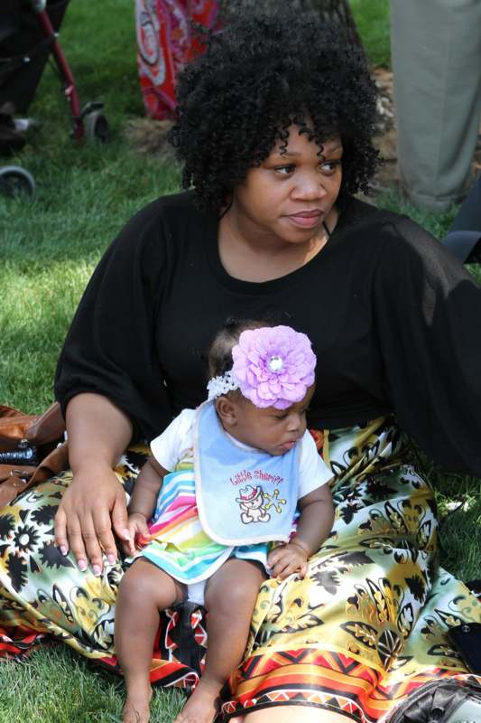 a woman sitting on the grass holding a baby