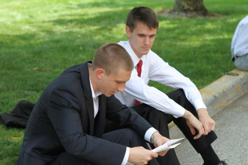 a couple of men sitting on a curb looking at something