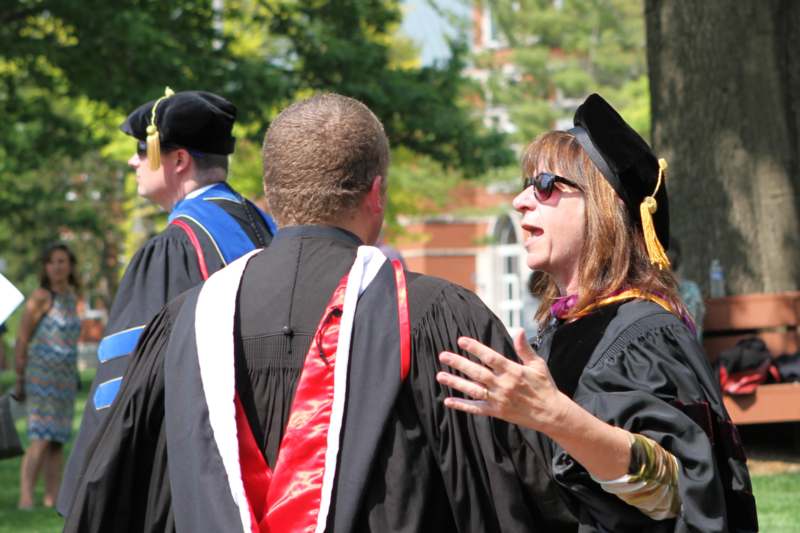 a woman in black gowns talking to a man in a graduation gown